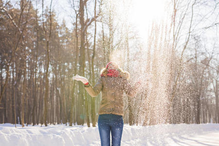美丽的女孩在寒冷的冬天公园里吹雪. 在户外. 飞舞的雪花.照片