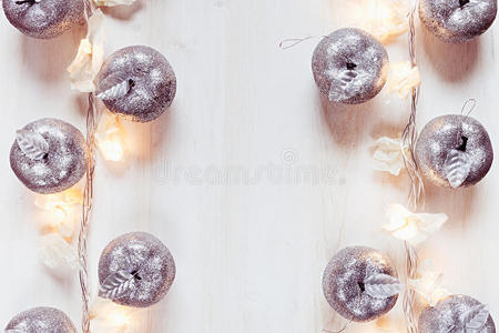 圣诞银苹果装饰和灯光在白色木质背景上燃烧。