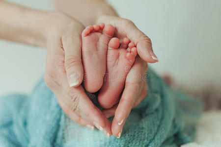 婴儿的脚在母亲手中。 雌性形状特写镜头上的微小新生儿。 妈妈和她的孩子。 幸福的家庭观念。 很漂亮