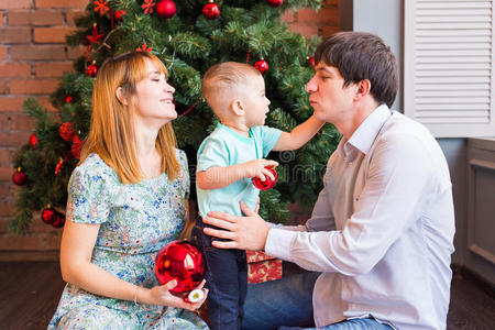 圣诞家庭带着孩子。 快乐微笑的父母和孩子在家里庆祝新年。 圣诞树。
