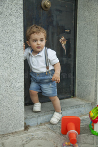 全镜头肖像可爱的小男孩站在房子门口附近