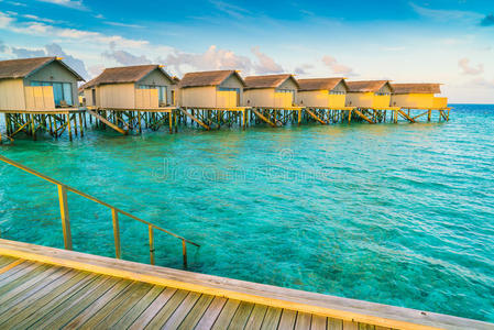 日出时热带马尔代夫岛美丽的水上别墅。