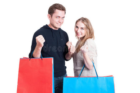 一对夫妇拿着购物袋做着获胜的手势