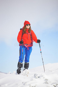 带着背包在山上雪地上行走的女孩。