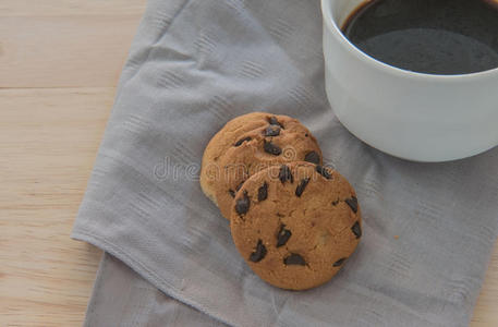 一块布上的巧克力饼干和木头背景上的咖啡。
