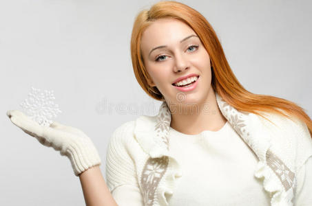 冬天穿衣服的女孩抱着一片大雪花微笑。