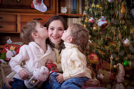 孩子们在圣诞树下亲吻他们的母亲