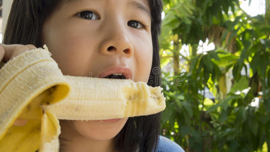 孩子吃香蕉亚洲欢乐咀嚼咬的概念照片
