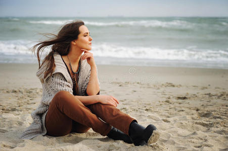平静的美丽女人独自坐在沙滩上看着水