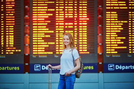 美丽的年轻旅游女孩，带着背包，在国际机场携带行李