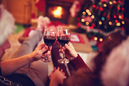一对夫妇带着红酒，靠着圣诞树和壁炉