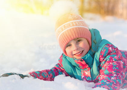 可爱的小女孩躺在雪亮的太阳上