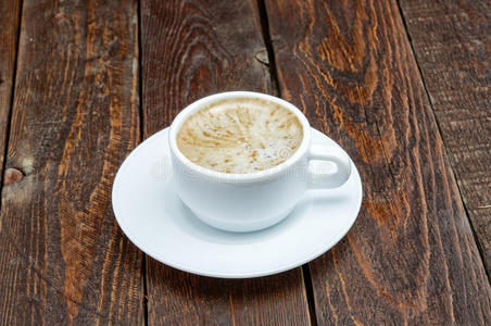 深色木桌上有泡沫的咖啡杯