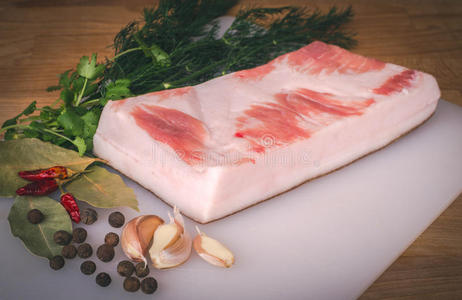 新鲜的生猪肉脂肪,准备在木制砧板,香料和草药上进行游戏照片