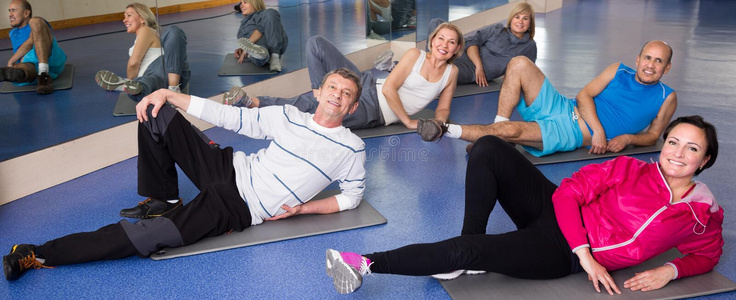 老年人在现代健身房的垫子上做运动照片