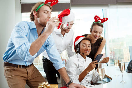 同事们在办公室庆祝圣诞聚会，喝着香槟，微笑着。