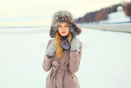 在冬天，时尚肖像女士穿着外套夹克和帽子在雪地上