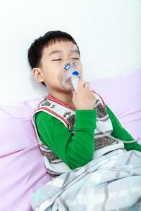 亚洲儿童闭上眼睛，拿着面罩蒸气吸入器治疗哮喘。