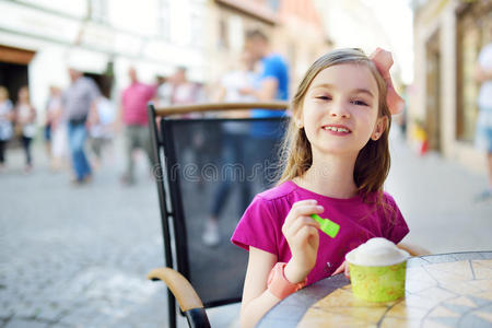 有趣的小女孩在夏天的户外咖啡馆里吃冰淇淋