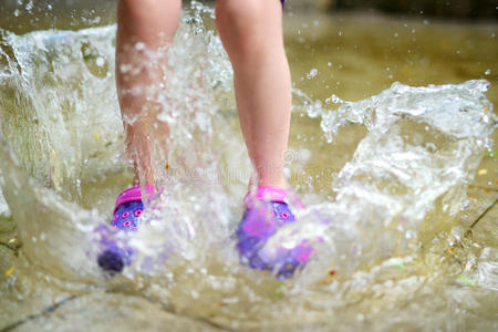 夏天，穿着橡胶鞋的孩子跳进水坑