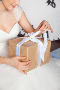 在婚礼庆典上拿着礼品盒的手。 工作室肖像美丽的新娘与礼物。布莱德拿着礼物。 圣诞节