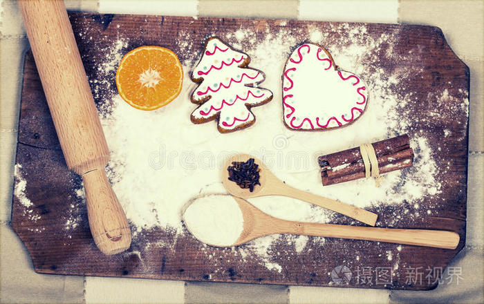 姜饼饼干，香料和面粉在木制切割板上