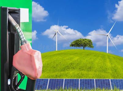 燃料喷嘴服务站与太阳能电池板，孤独的树木和风力涡轮机在绿色领域