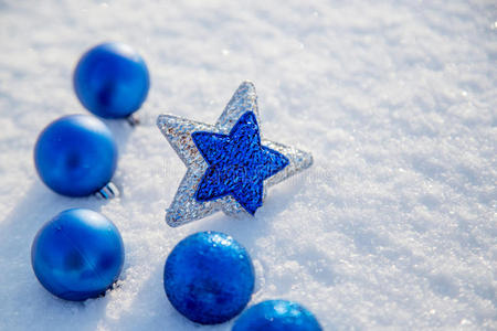在阳光明媚的日子里，圣诞蓝球和星星在雪地里