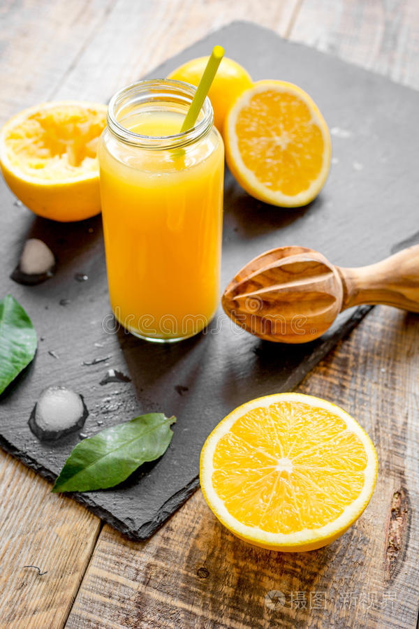 在木制背景上的玻璃瓶中新鲜挤压橙汁