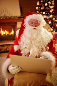 圣诞老人拿着笔记本电脑在客厅里