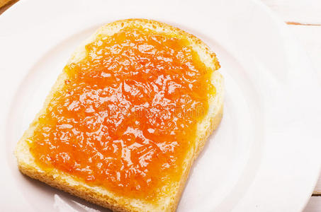 预存物业费盘子里有橙色桃子果酱的面包照片