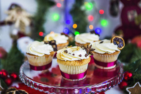 蛋糕，纸杯蛋糕与干柠檬和巧克力在玻璃上站在绿色圣诞花环和灯光的背景上