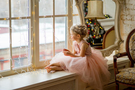 坐在窗边的可爱的小女孩