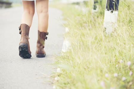 美丽的女人穿着棕色的靴子走在路上
