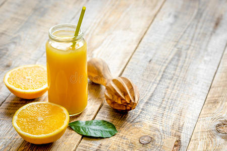 在木制背景上的玻璃瓶中新鲜挤压橙汁