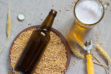 棕色玻璃瓶。 小麦陶瓷板。 一杯啤酒和麦穗的零食。