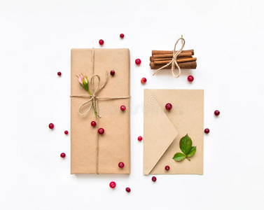 白色背景的生态纸礼品盒和信封。 用玫瑰和浆果装饰的礼物。 假日概念，顶景，平面