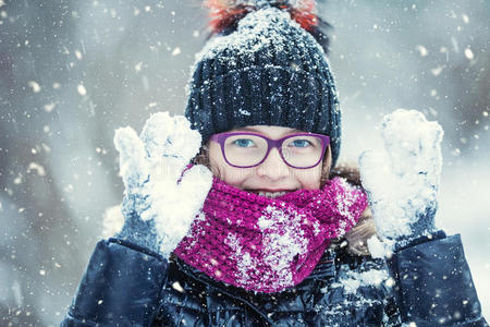 美丽的冬天快乐的女孩在寒冷的冬天公园或户外吹雪。 女孩和冬天寒冷的天气