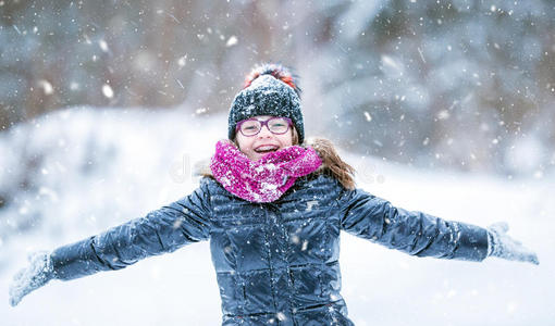 美丽的冬天快乐的女孩在寒冷的冬天公园或户外吹雪。 女孩和冬天寒冷的天气