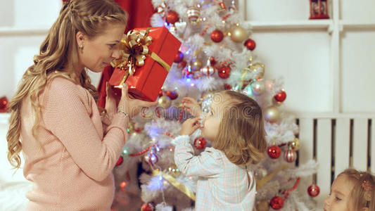 家庭由坐在圣诞树周围带礼物的女性组成