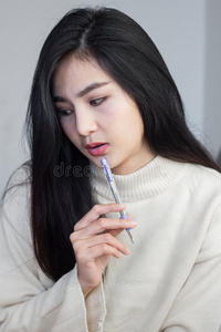 亚洲女孩思考并拿着一支笔.照片
