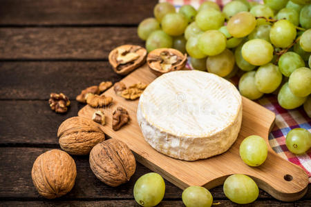 卡曼伯特奶酪与核桃和绿色葡萄在木制乡村背景