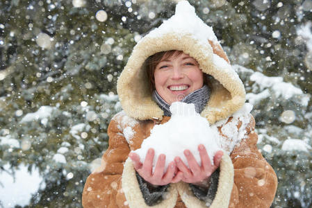 美丽的女人在冬天的户外玩雪，森林里的雪杉树，穿着羊皮外套