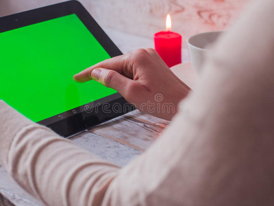 特写女性手拿着一台绿色屏幕平板电脑在咖啡馆