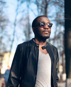 时尚肖像非洲男子戴太阳镜，黑色岩石皮夹克在街上