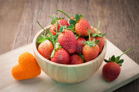 新鲜成熟草莓在木盘上，心形橙色