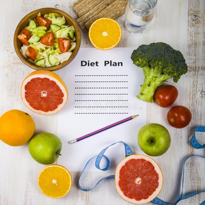 食物和一张纸，上面有一张木制桌子上的饮食计划。 饮食和健康生活方式的概念。