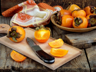 美味的成熟橙色柿子在碗中的木制背景。