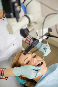 女牙医在牙科办公室用显微镜治疗龋病