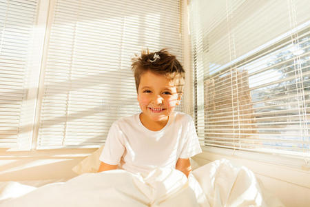 可爱的男孩醒在充满阳光的白色卧室里